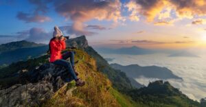 Traveller sitting on the rock and holding camera take photo at Doi pha mon mountains in Chiang rai, Thailand.